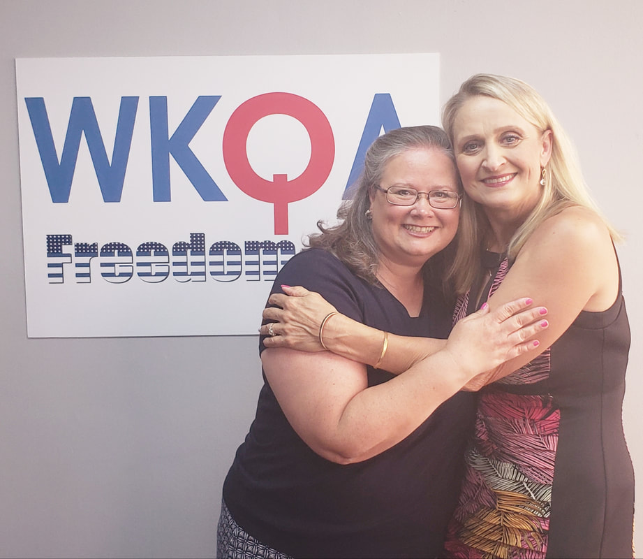 Christine Tate and Christine Bacon hug underneath the WKQA sign in the Norfolk studios.