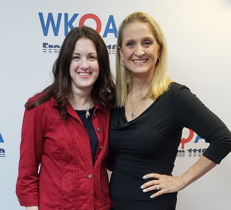 Dr. Christine bacon and her guest pose in front of the WKQA sign in the Hampton Roads studio.