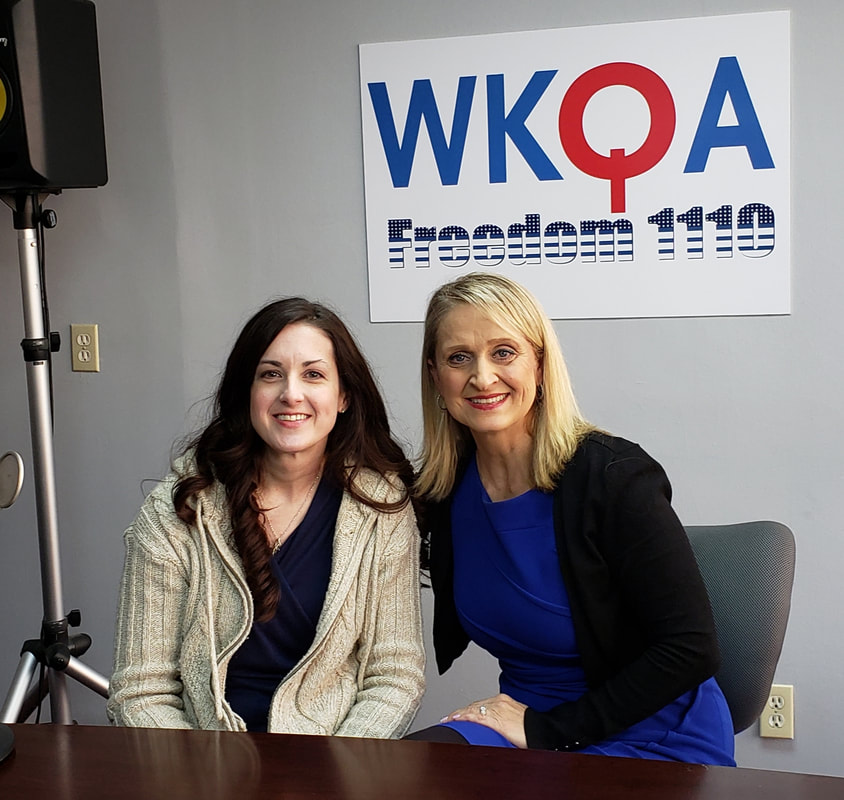 Dr. Christine Bacon and Jenifer Hartline sitting behind the broadcast desk in the WKQAstudios.
