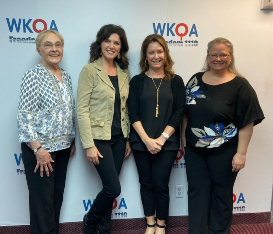 Four gorgeous ladies smiling under the WKQA sign in the studio.