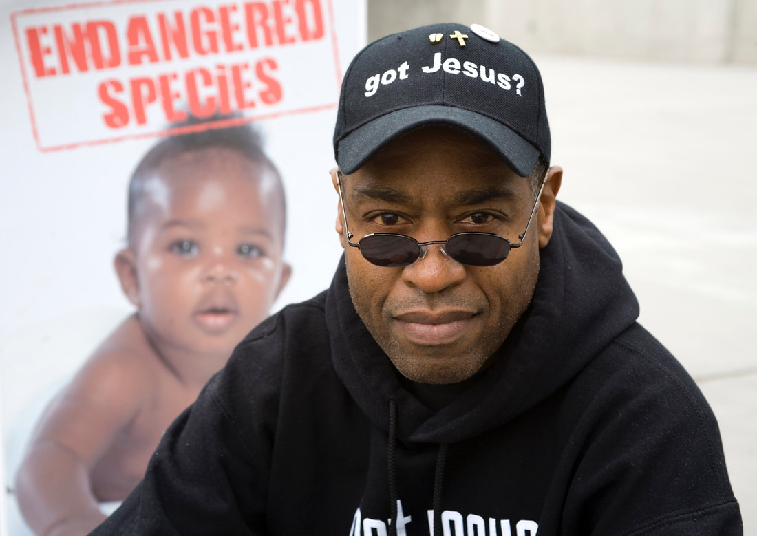 Walter Hoye in foreground with image of black baby behind him with captions 