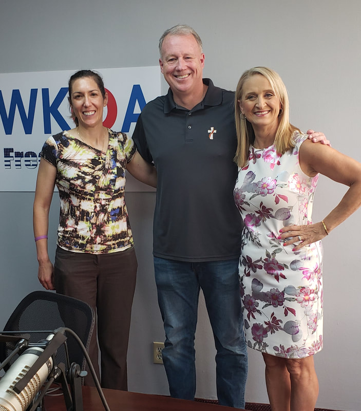 Lisa, Dave and Dr. Bacon stand together under the WKQA sign in the Hampton Roads studios.