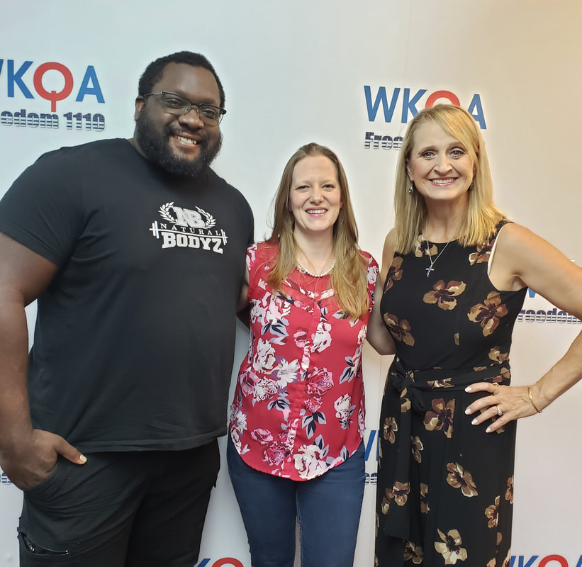 Joacob, Jessica and Dr. Christine bacon stand under the WKQA sign in the radio studio.