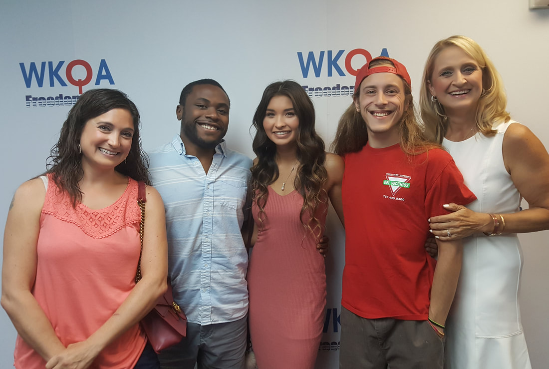 The group of guests stand arm and arm with Dr. Bacon in the WKQA studios. 